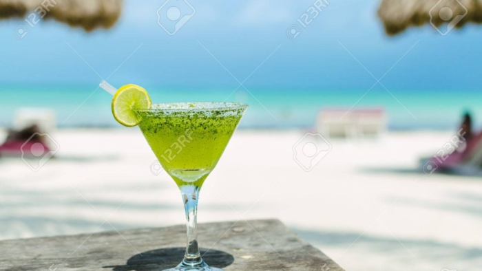 Fresh cold tasty Margarita cocktail with lime and ice on a table at tropical white sand beach